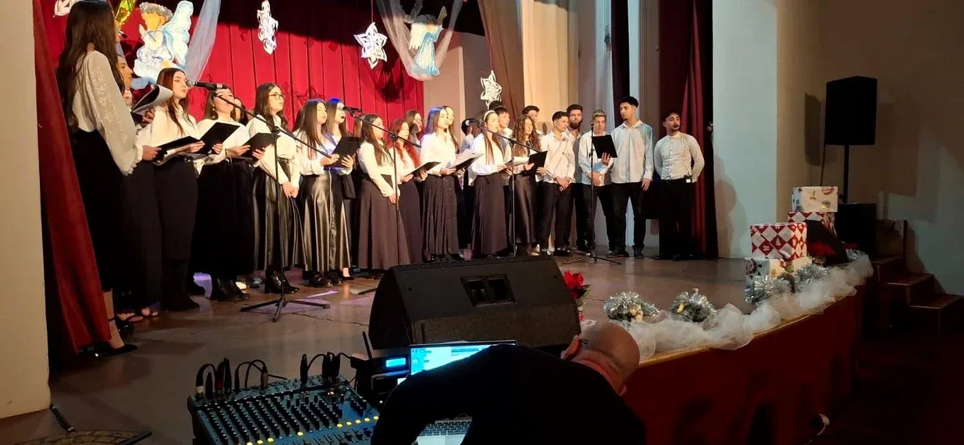 Grup de elevi cântând pe scenă la un spectacol festiv