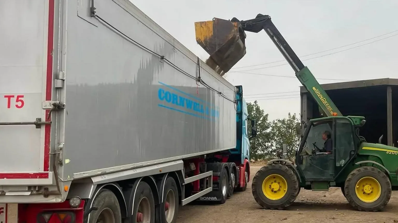 Încărcător telescopic ridică marfă într-o semiremorcă agricolă