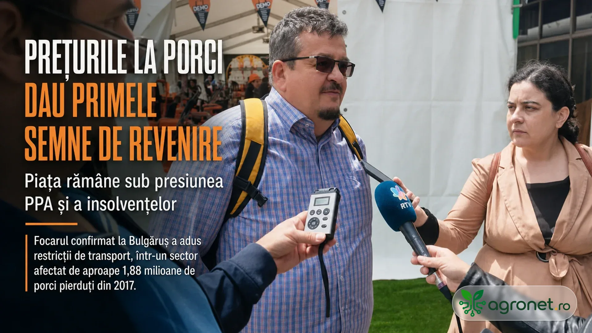 Bărbat intervievat de reporteri, cu microfon și reportofon, lângă un panou cu text despre piața porcilor.