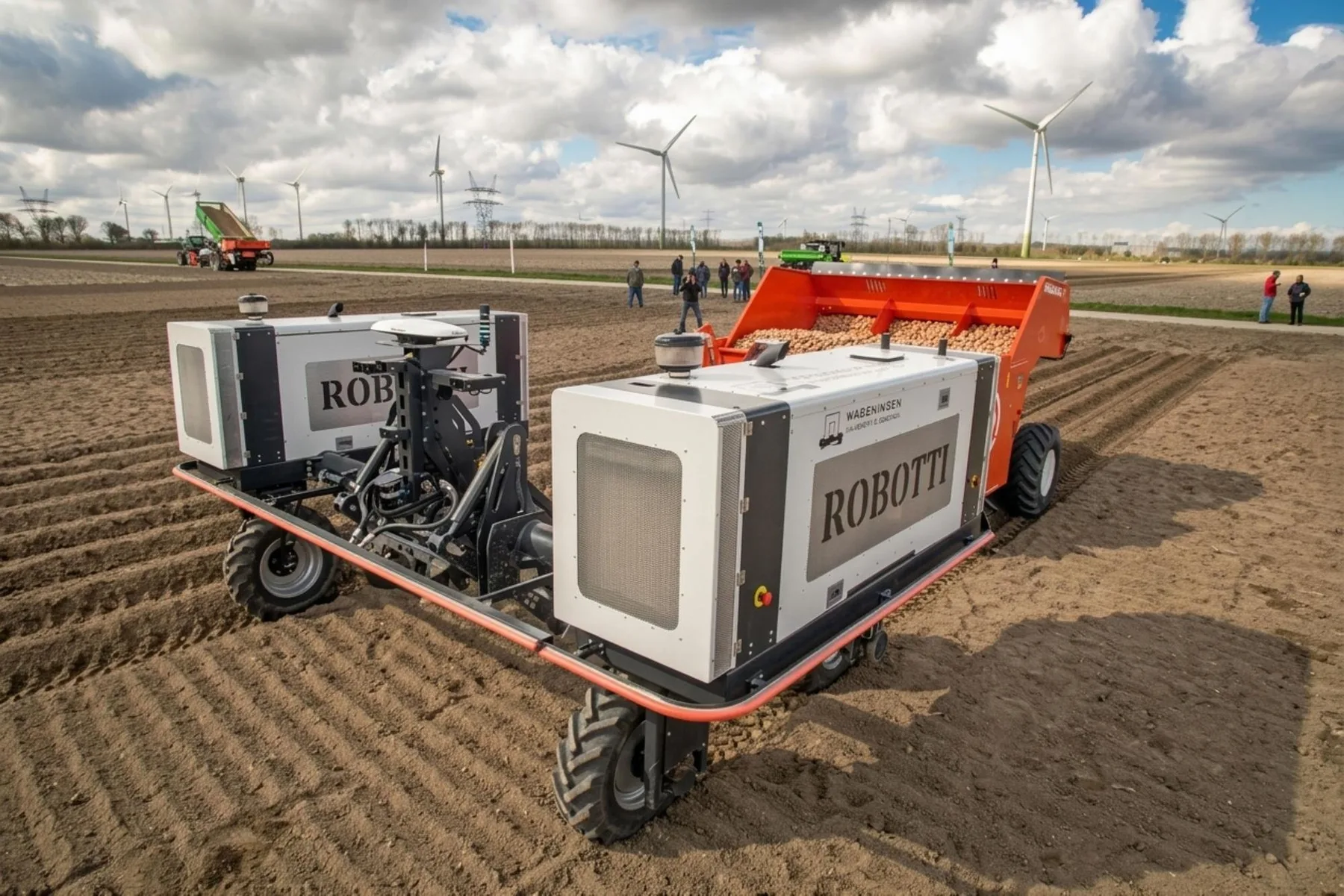 Roboți agricoli Robotti lucrează pe câmp, lângă turbine eoliene