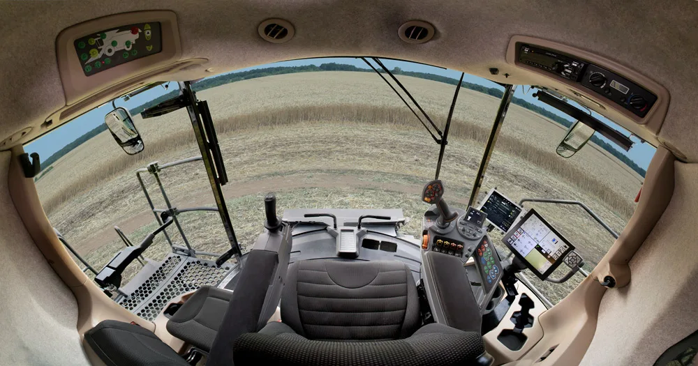 Cabină de utilaj agricol modern, cu monitoare și câmp în față