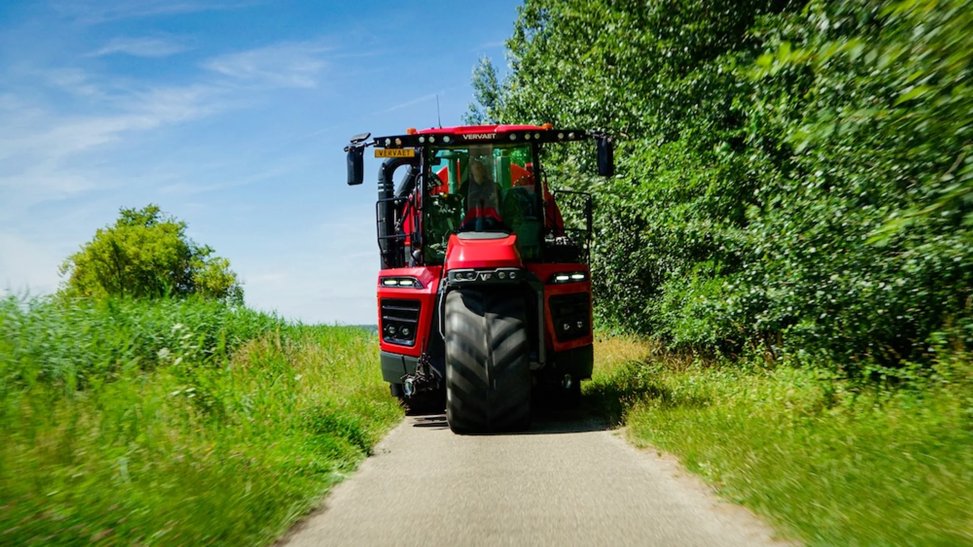 Automotor Vervaet roșu pe drum îngust, între vegetație densă