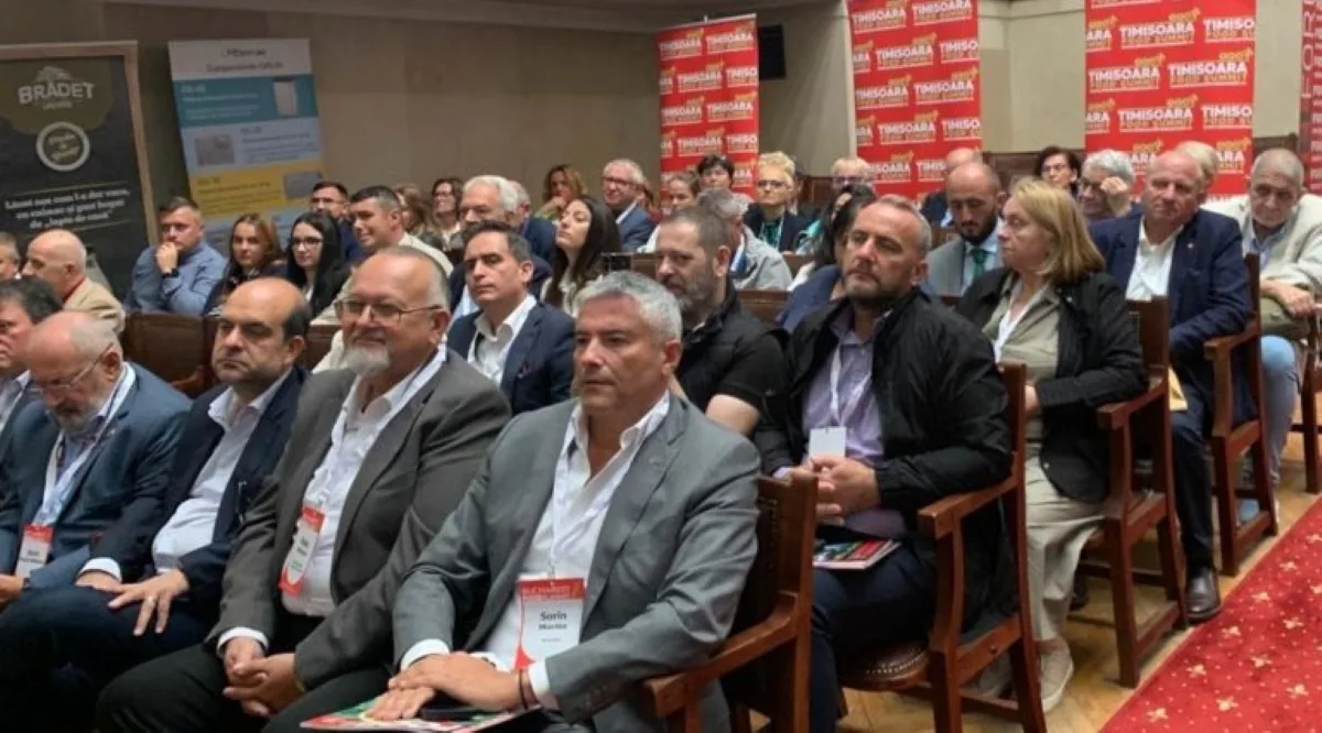 Participanți la conferință, așezați în sală, cu ecusoane la gât
