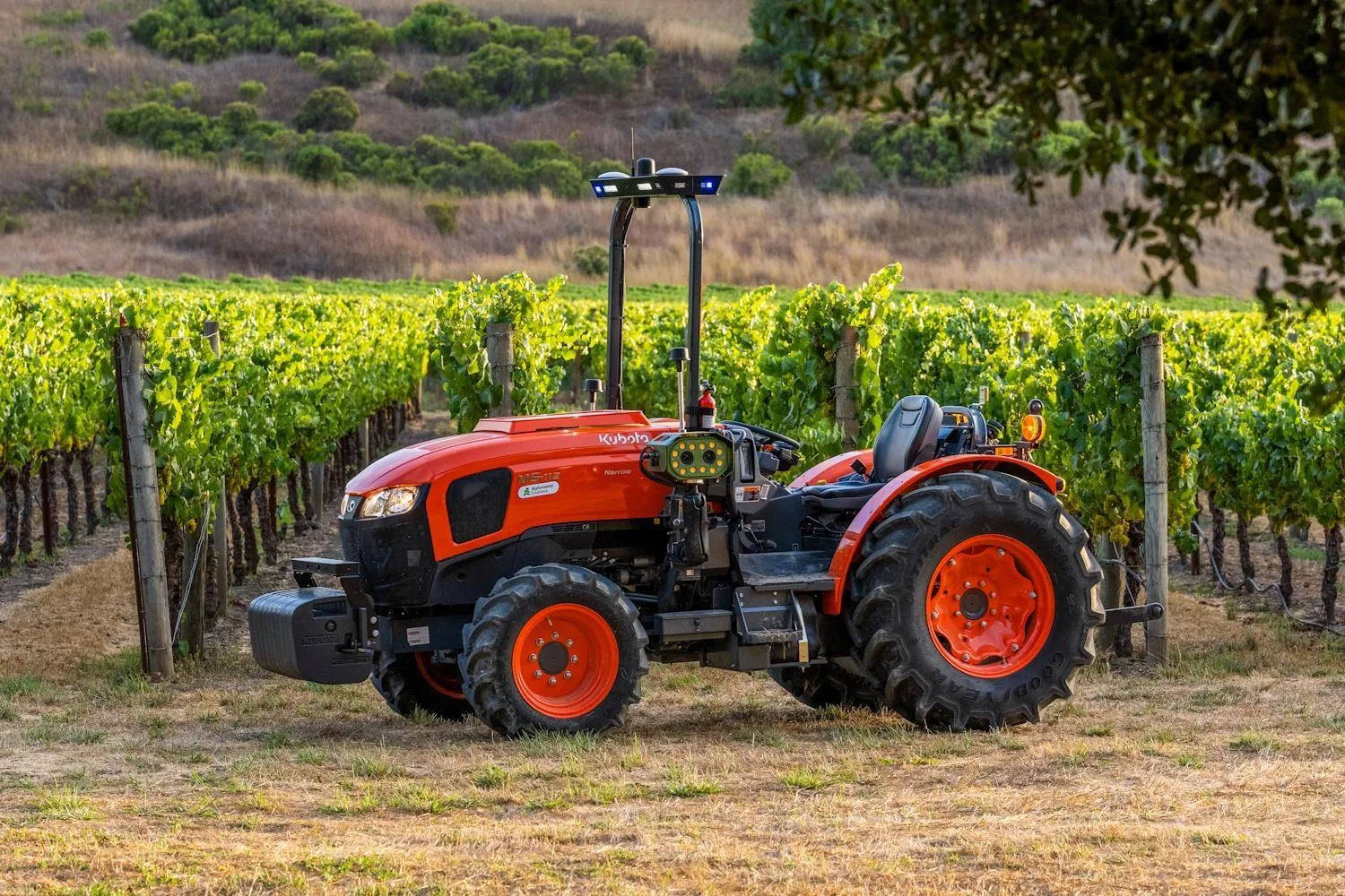 Tractor Kubota portocaliu echipat cu senzori, staționat între rânduri de viță