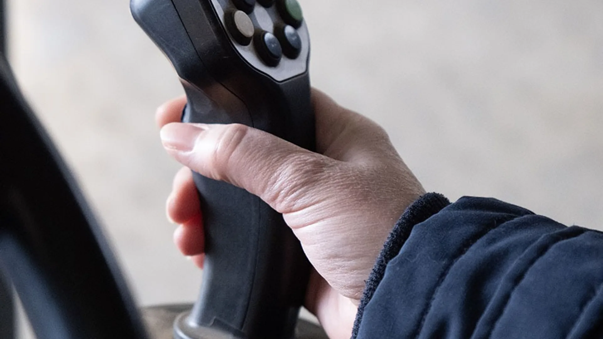 Mână pe joystickul de comandă din cabina unui utilaj agricol