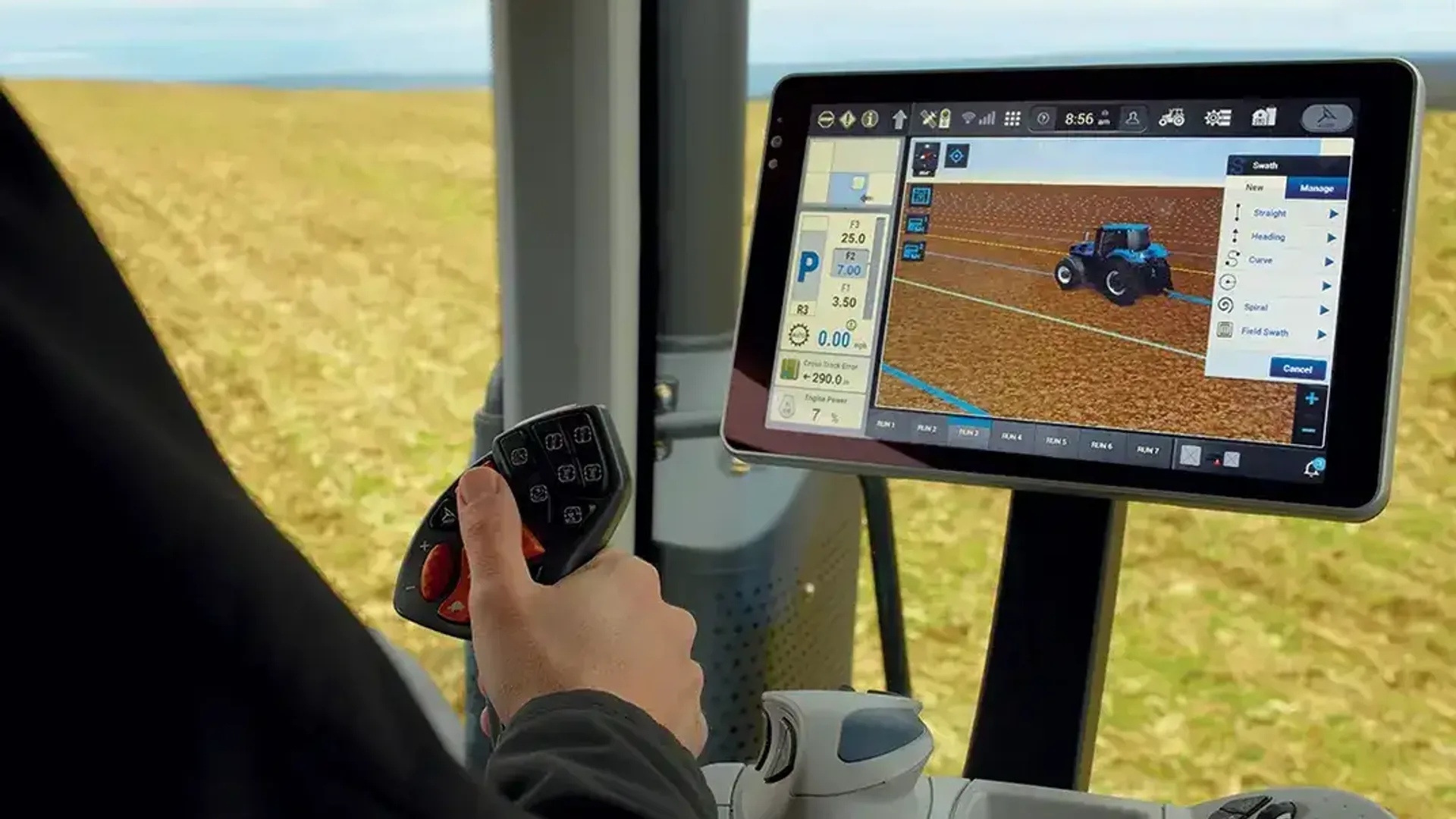 Operator într-o cabină de tractor, ținând joystickul lângă un monitor cu interfață de ghidare pe câmp.