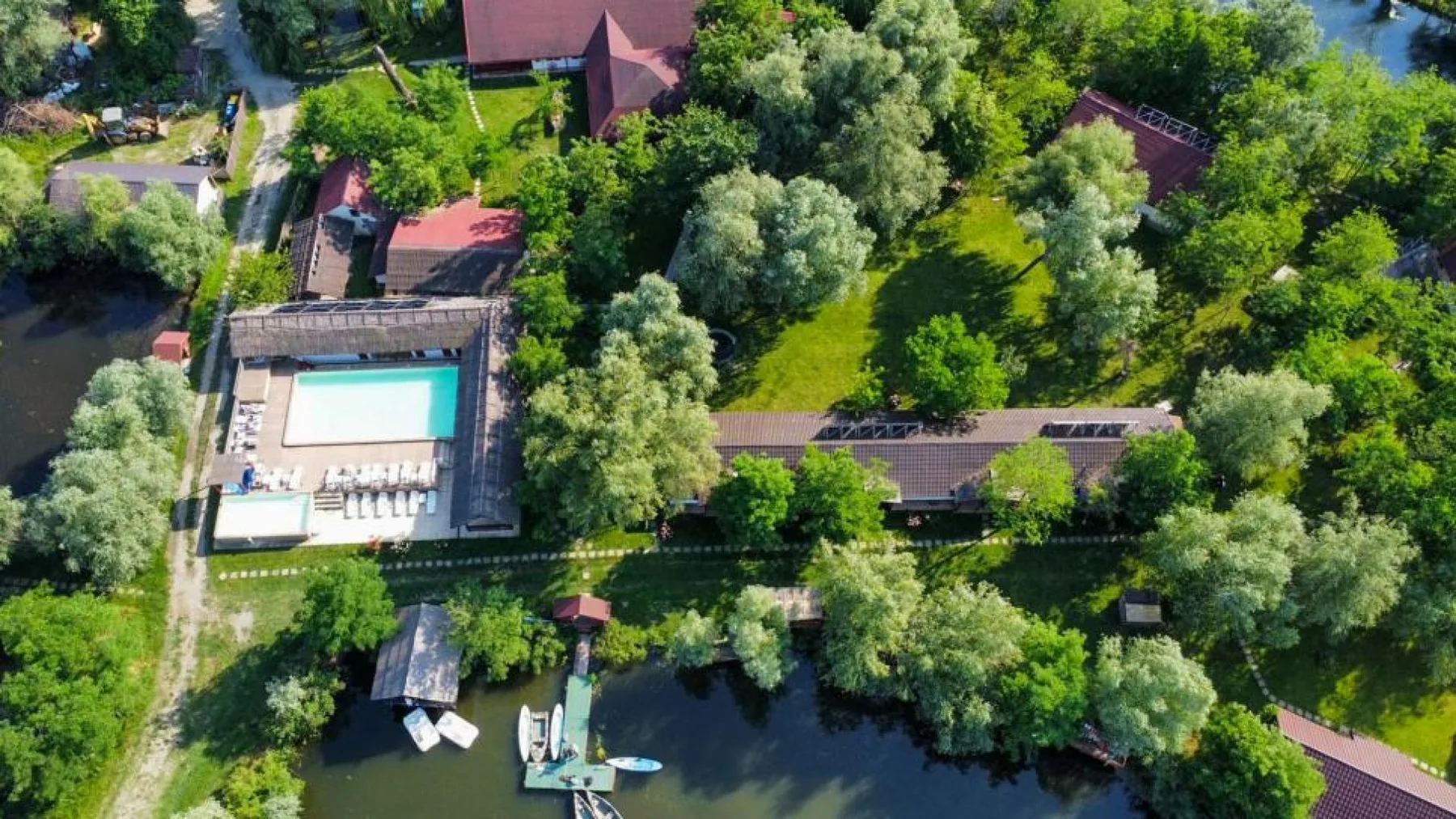 Vedere aeriană asupra resortului cu piscină, pontoane și vegetație deasă
