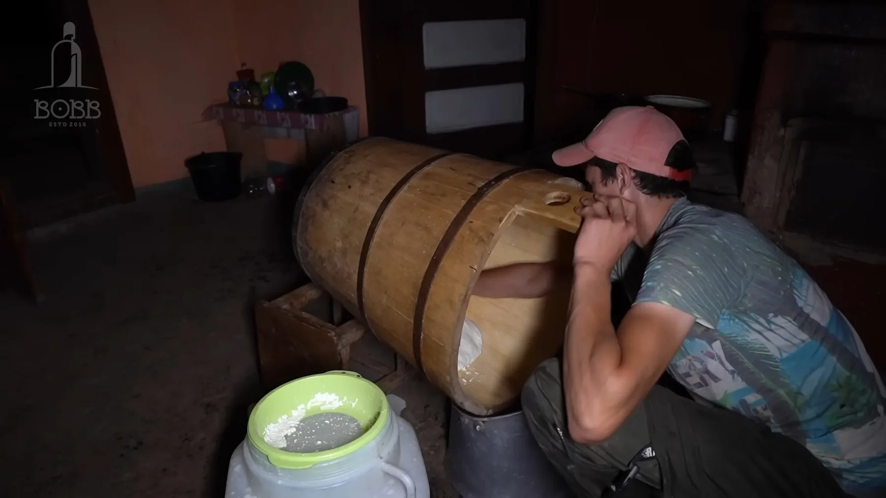 Tânăr lângă putinei de lemn, lucrând la prepararea cașului