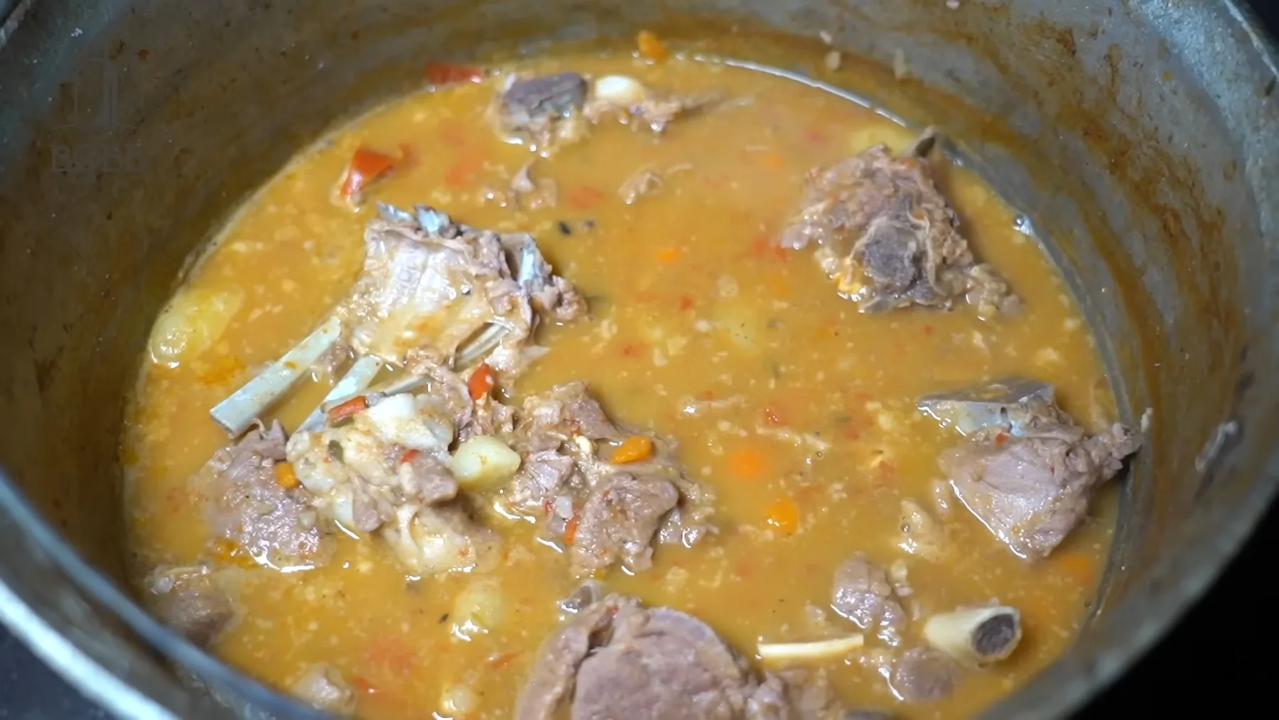 Tocană cu bucăți de carne și legume într-un ceaun metalic