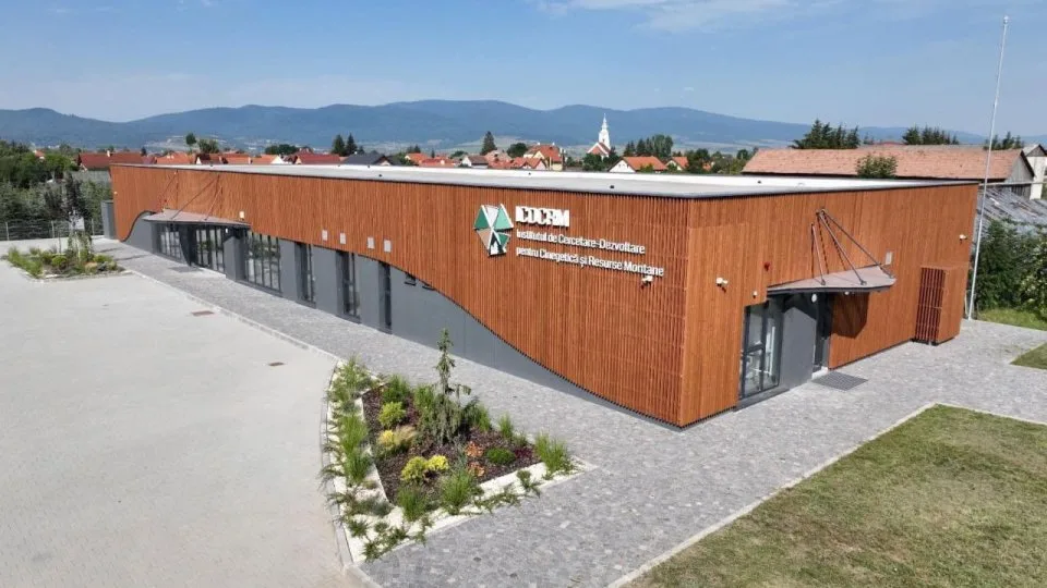 Clădire modernă ICDCRM, cu fațadă din lemn și munți în fundal