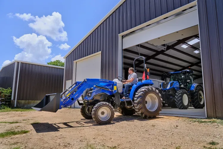 Tractor compact New Holland cu încărcător frontal, la ieșirea din hală
