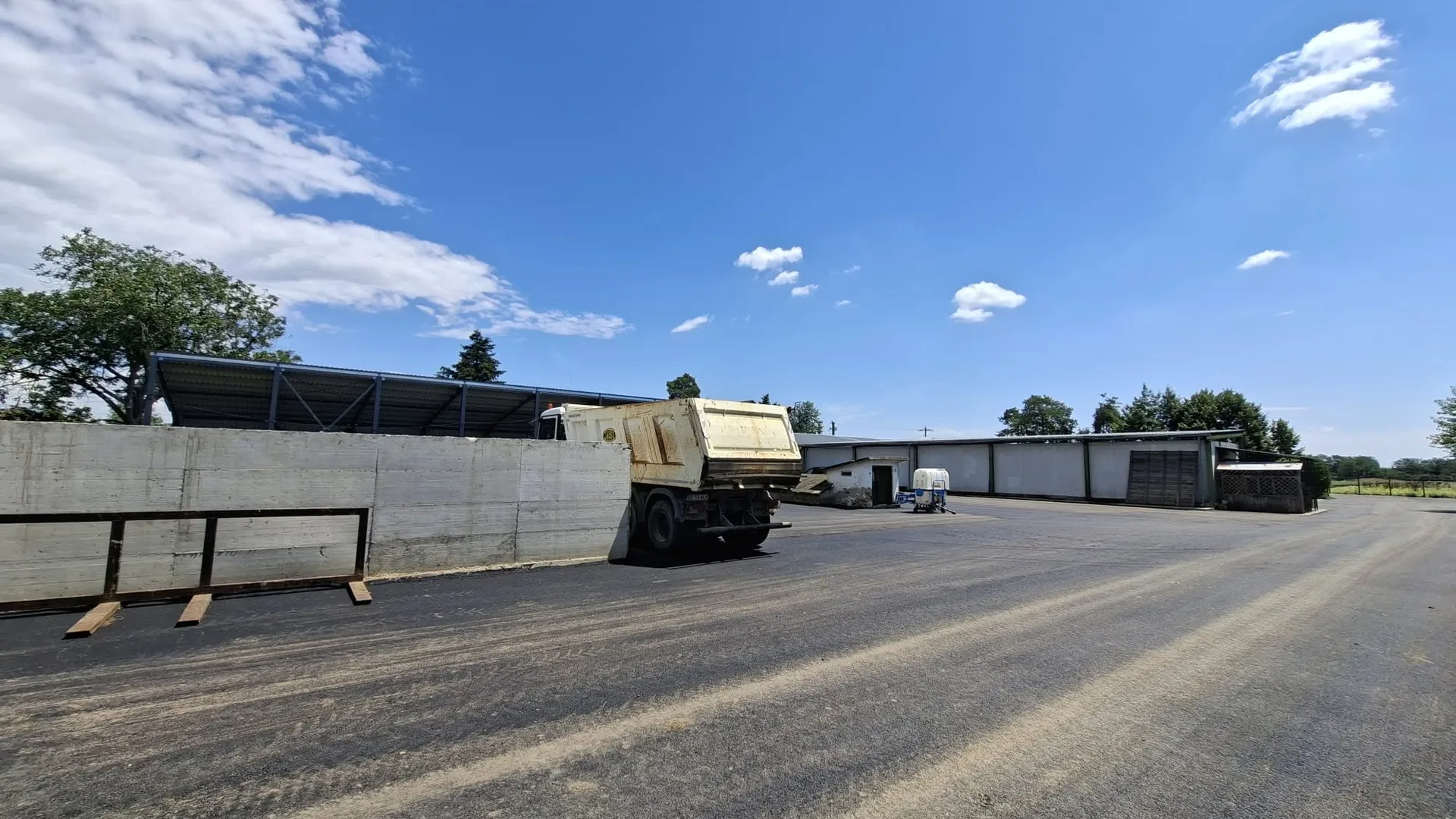 Curte asfaltată cu camion, ziduri de beton și clădiri joase