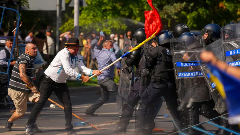 Protestatar lovește cu un steag cordonul de jandarmi cu scuturi