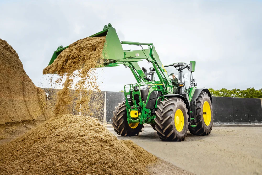 Tractor John Deere cu încărcător frontal descarcă furaj într-un siloz