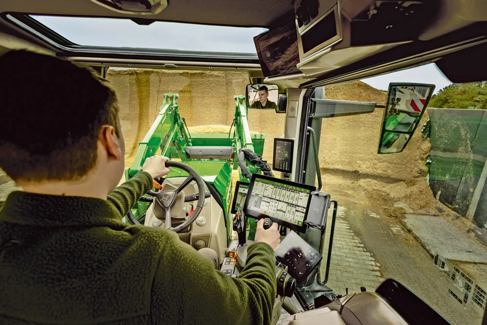 Operator în cabina tractorului, folosind terminalul lângă baloți de paie