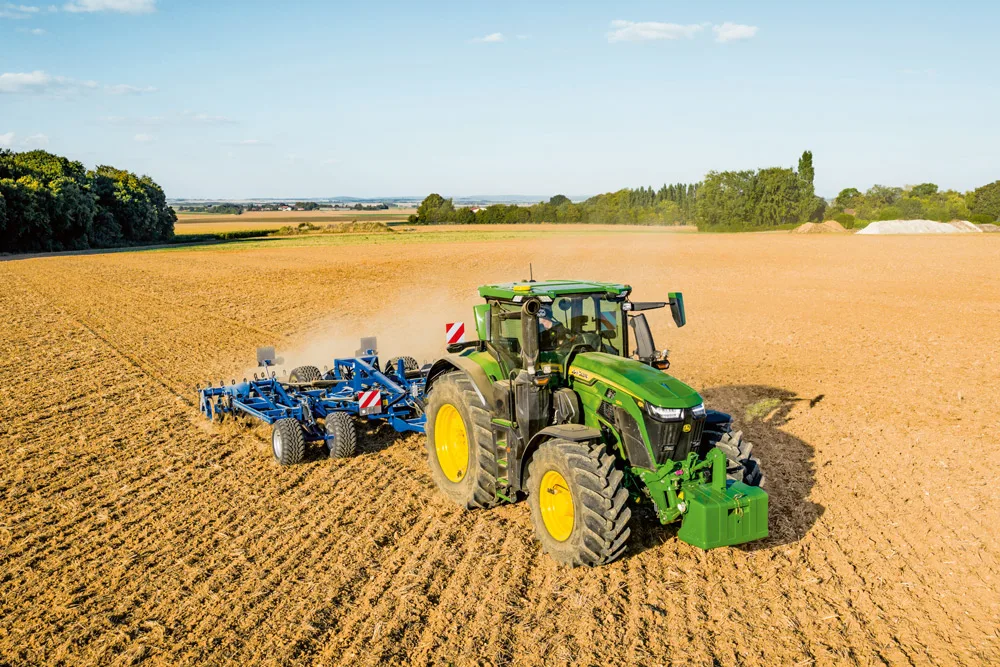 Tractor John Deere tractând un cultivator pe un câmp arat