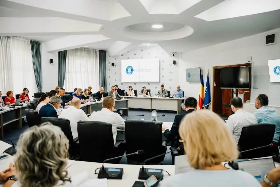 Ședință oficială într-o sală de conferințe, cu participanți așezați la mese