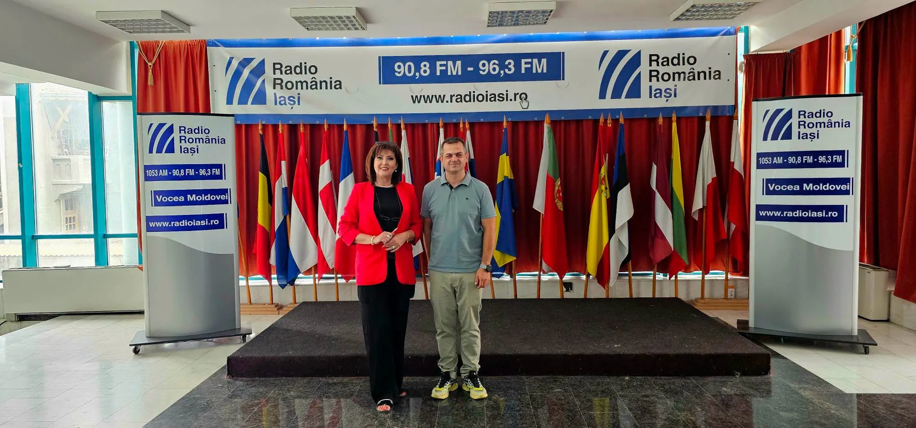 Două persoane stau în fața bannerelor Radio România Iași