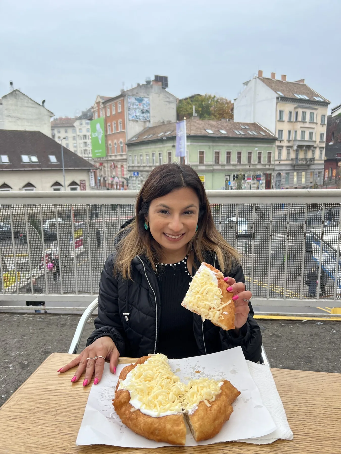 Femeie la terasă ținând lángos cu brânză rasă
