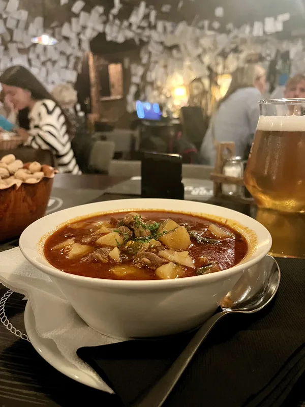 Bol cu gulaș și halbă de bere pe masă de restaurant