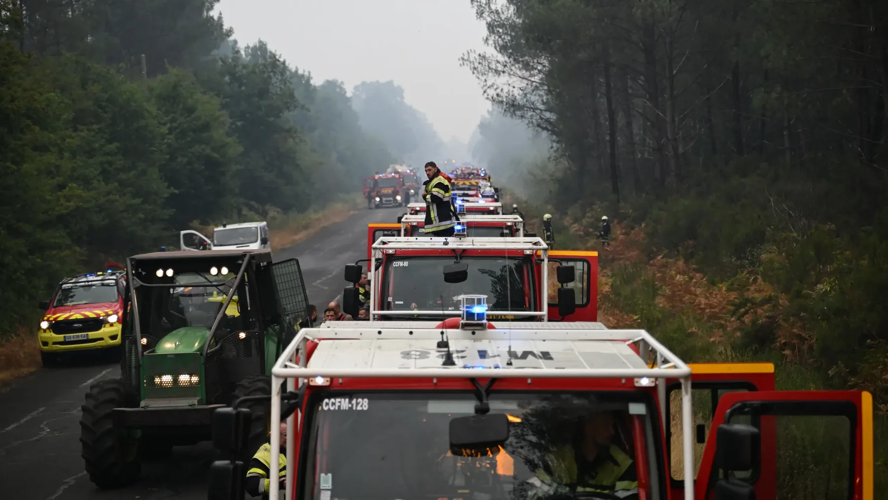 Convoi de autospeciale și vehicule de intervenție pe șosea forestieră fumegândă