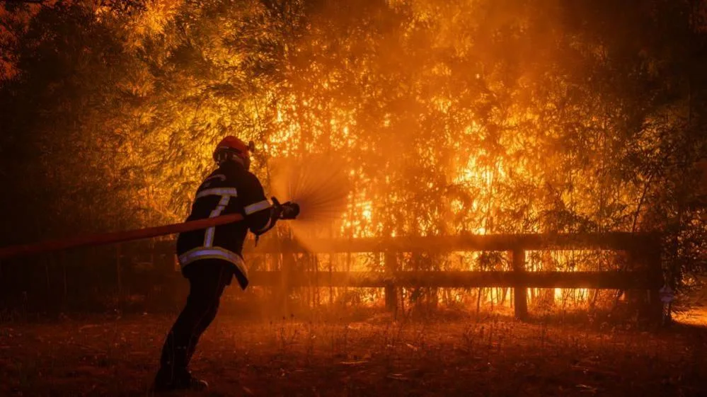 Pompier stropește cu furtunul vegetația cuprinsă de flăcări intense