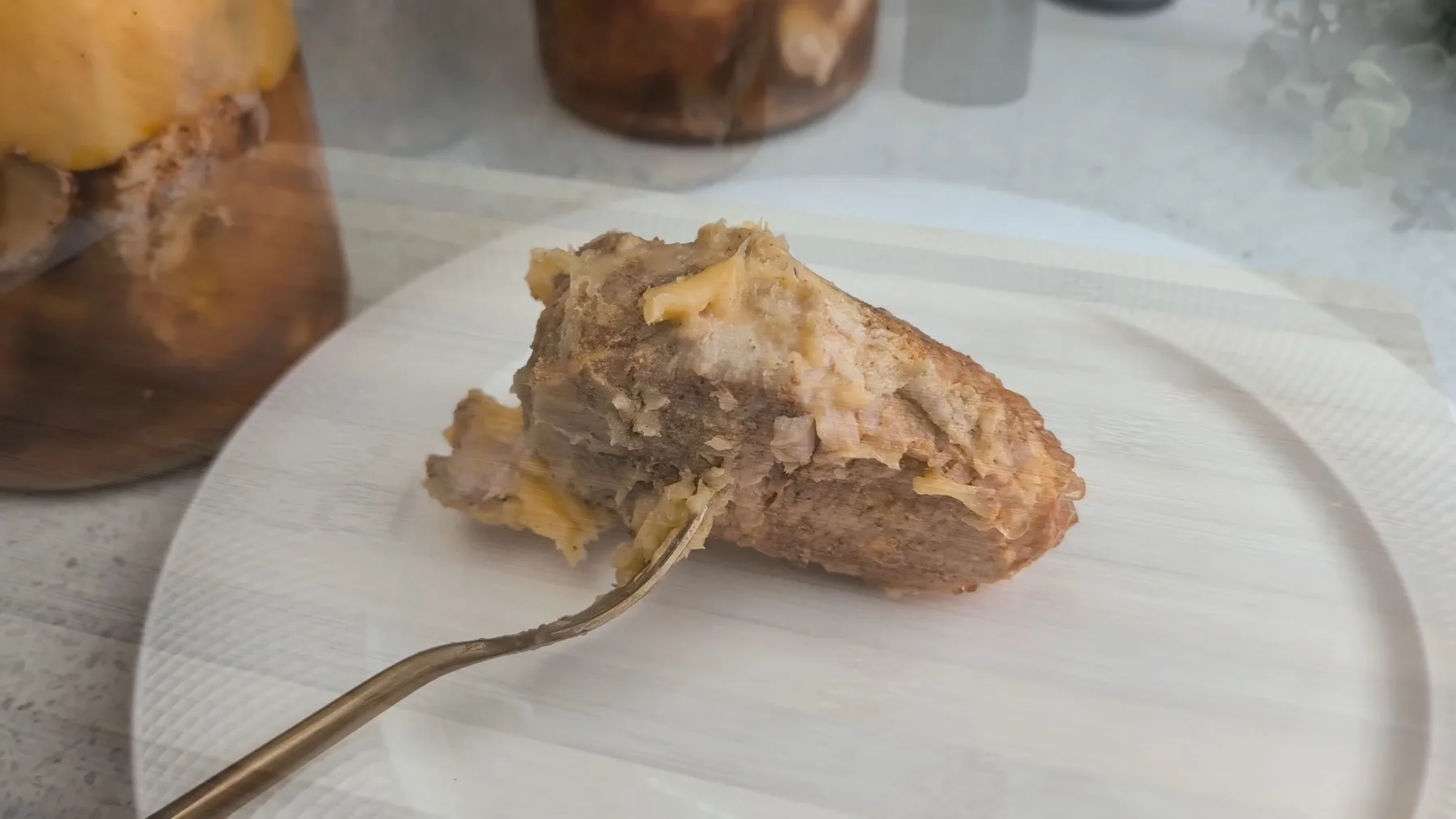 Bucată de carne de porc conservată, scoasă pe furculiță lângă borcane