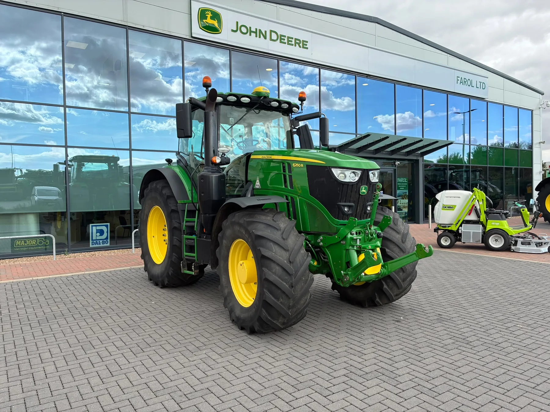 Tractor John Deere expus în fața unui showroom de utilaje agricole