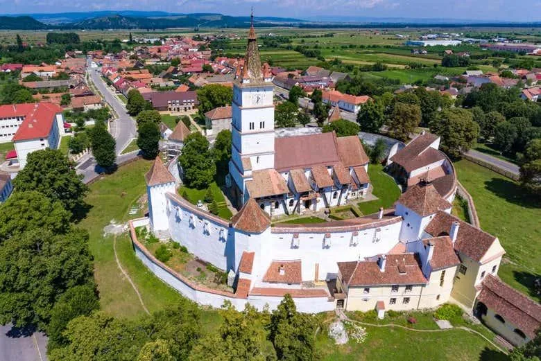 Biserica fortificată din Hărman văzută aerian, înconjurată de sat și câmpuri