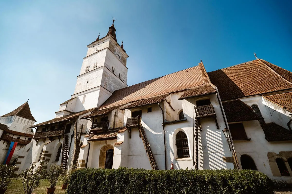 Turnul-clopotniță și zidurile bisericii fortificate din Hărman sub cer senin