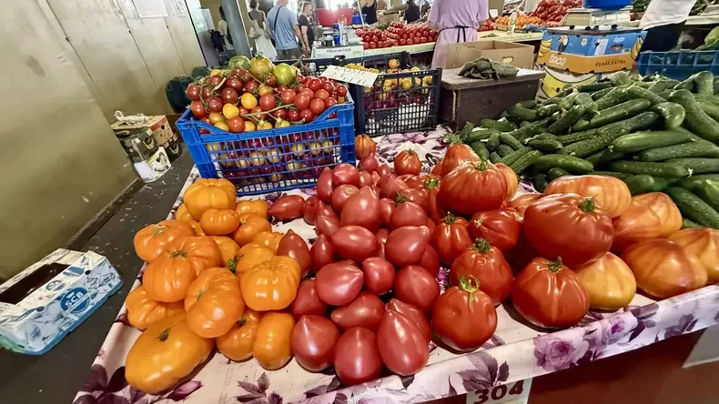 Roșii colorate și castraveți expuși la tarabă într-o piață