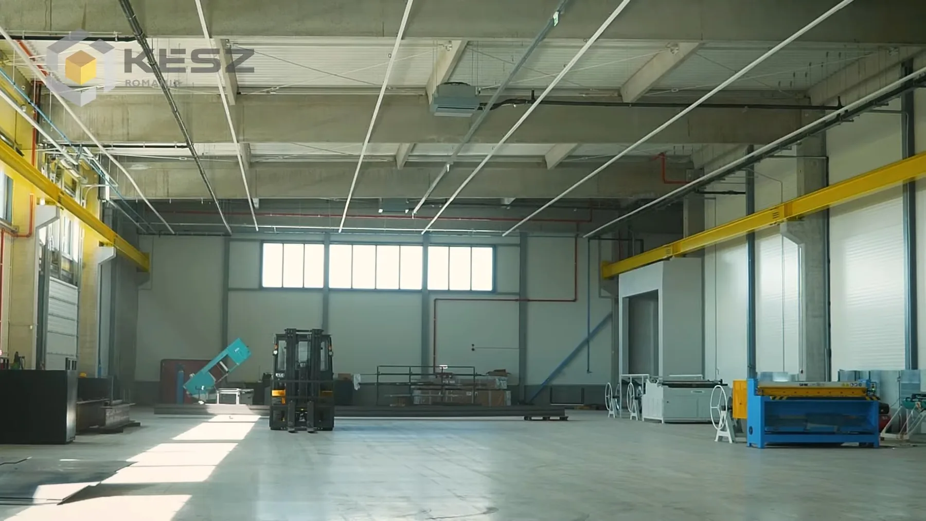 Hală industrială goală, cu motostivuitor și poduri rulante galbene