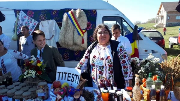 Femeie în ie la stand cu brânzeturi, borcane și decorațiuni tradiționale