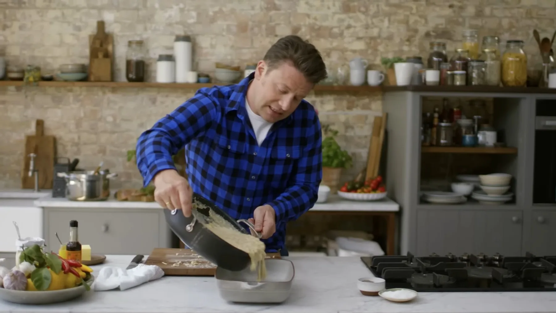 Jamie Oliver toarnă macaroane cu sos într-un vas pentru cuptor