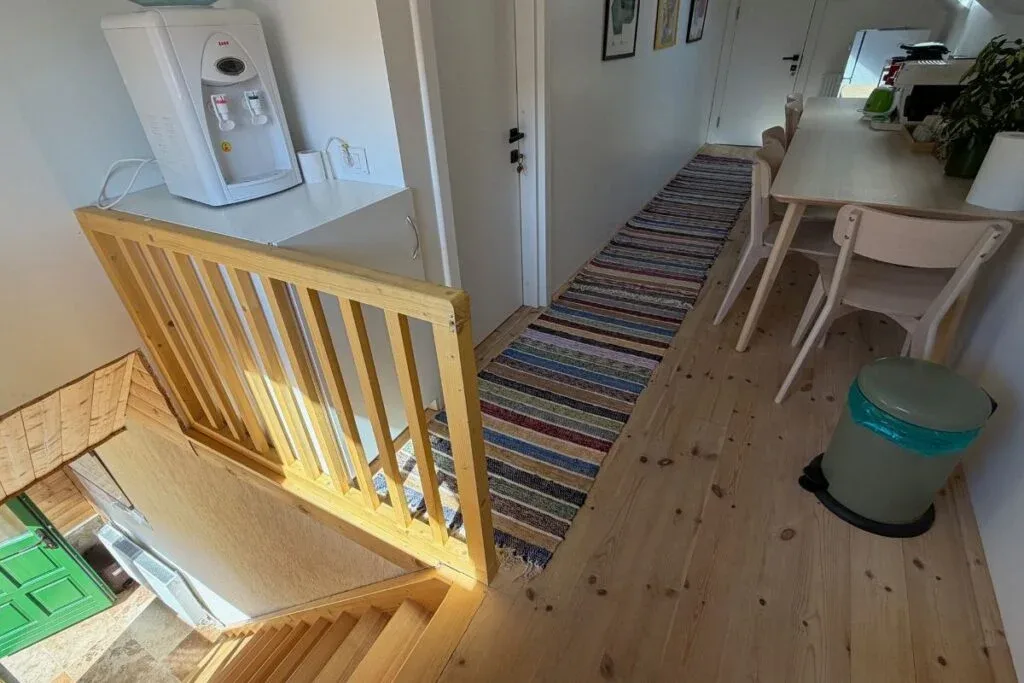 Interior renovat cu scară din lemn, covor țesut și zonă de luat masa