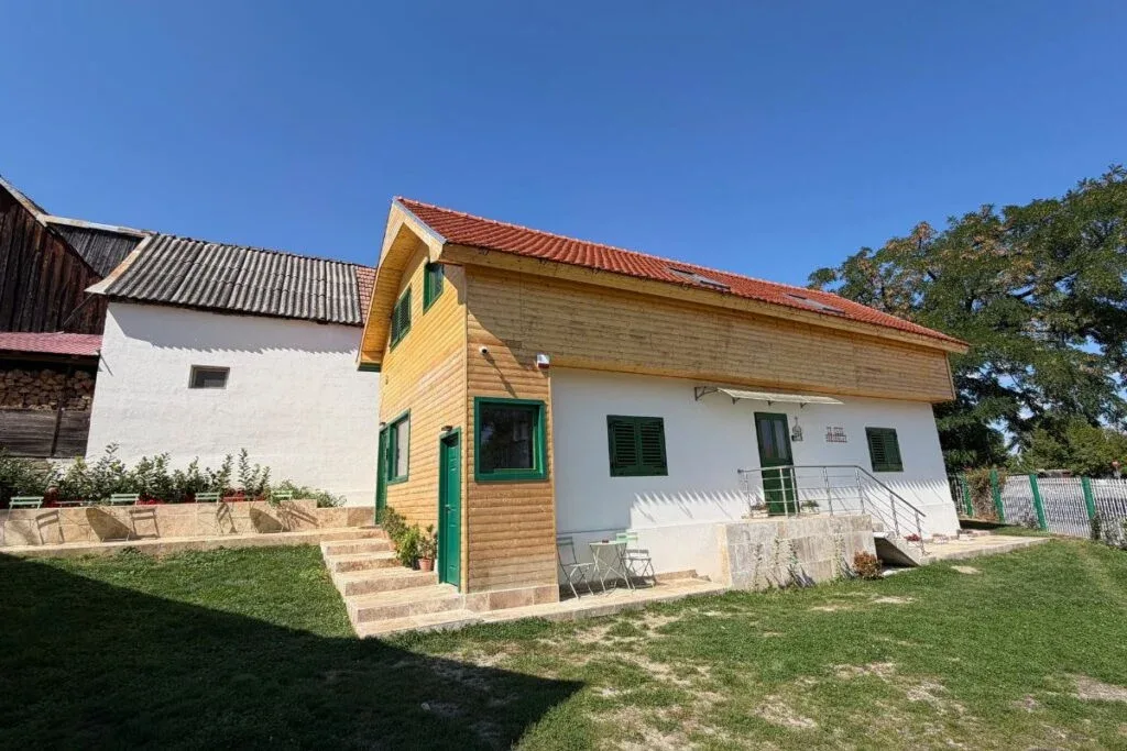 Clădirea morii restaurate, cu obloane verzi și acoperiș roșu
