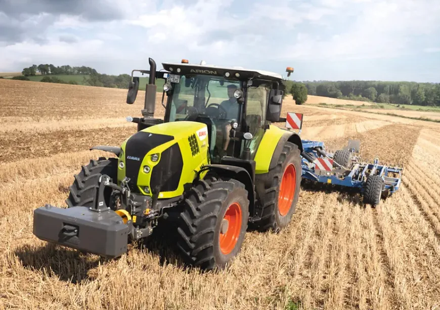 Tractor CLAAS ARION lucrează miriștea cu utilaj albastru pe câmp