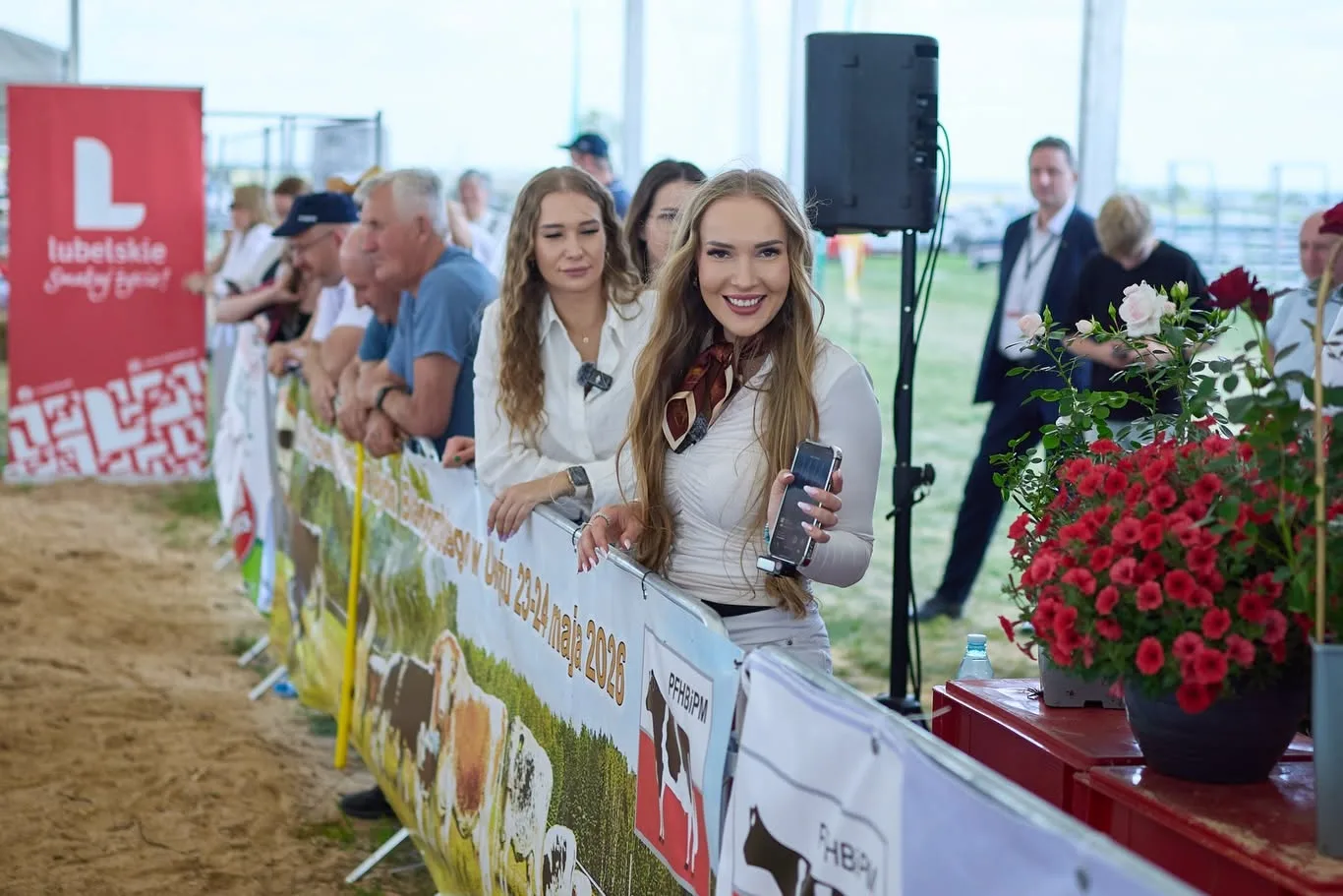 Vizitatori la stand agricol, lângă bannere și flori decorative