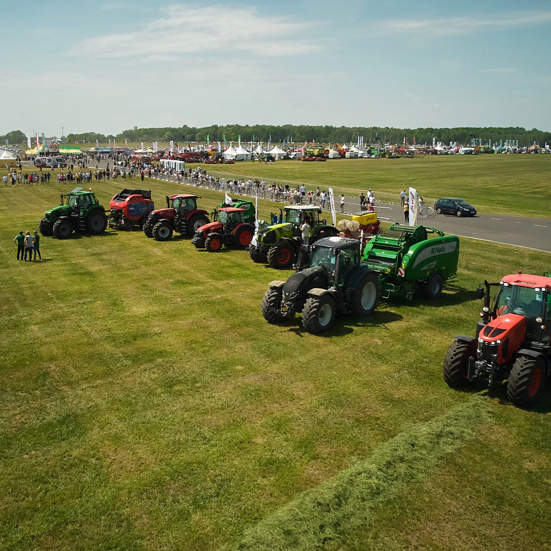 Tractoare și utilaje agricole expuse pe câmp, la un târg în aer liber