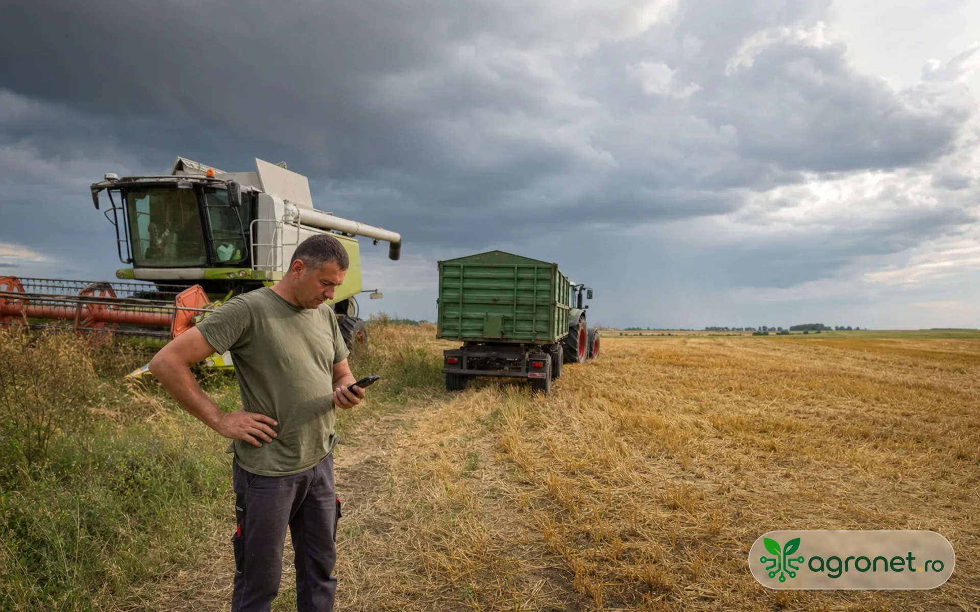 Fermier verificând prognoza pe telefon lângă o combină oprită la marginea unui lan, într-o zi de vară cu nori de furtună.