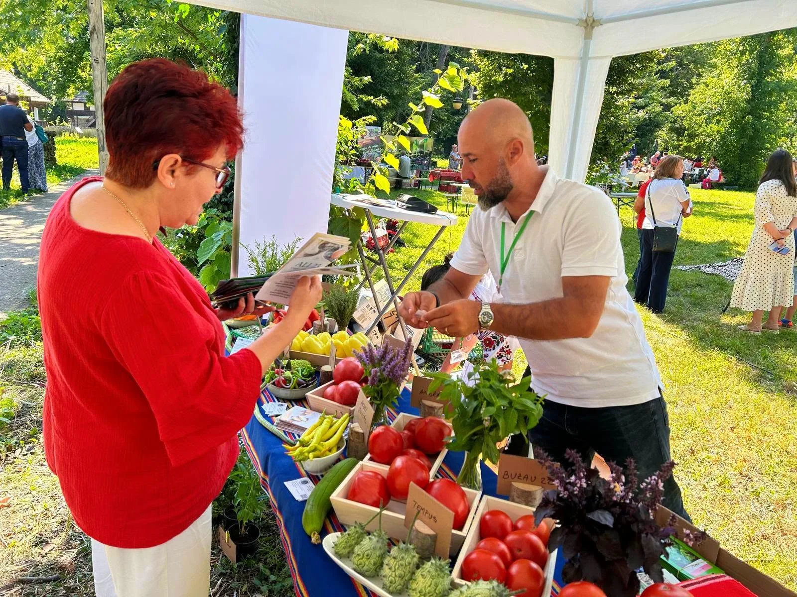 Bărbat explică unei vizitatoare exponatele de legume și tomate