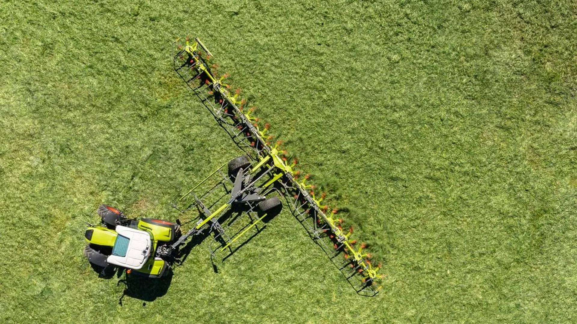 Vedere aeriană cu tractor și greblă de împrăștiat pe pajiște