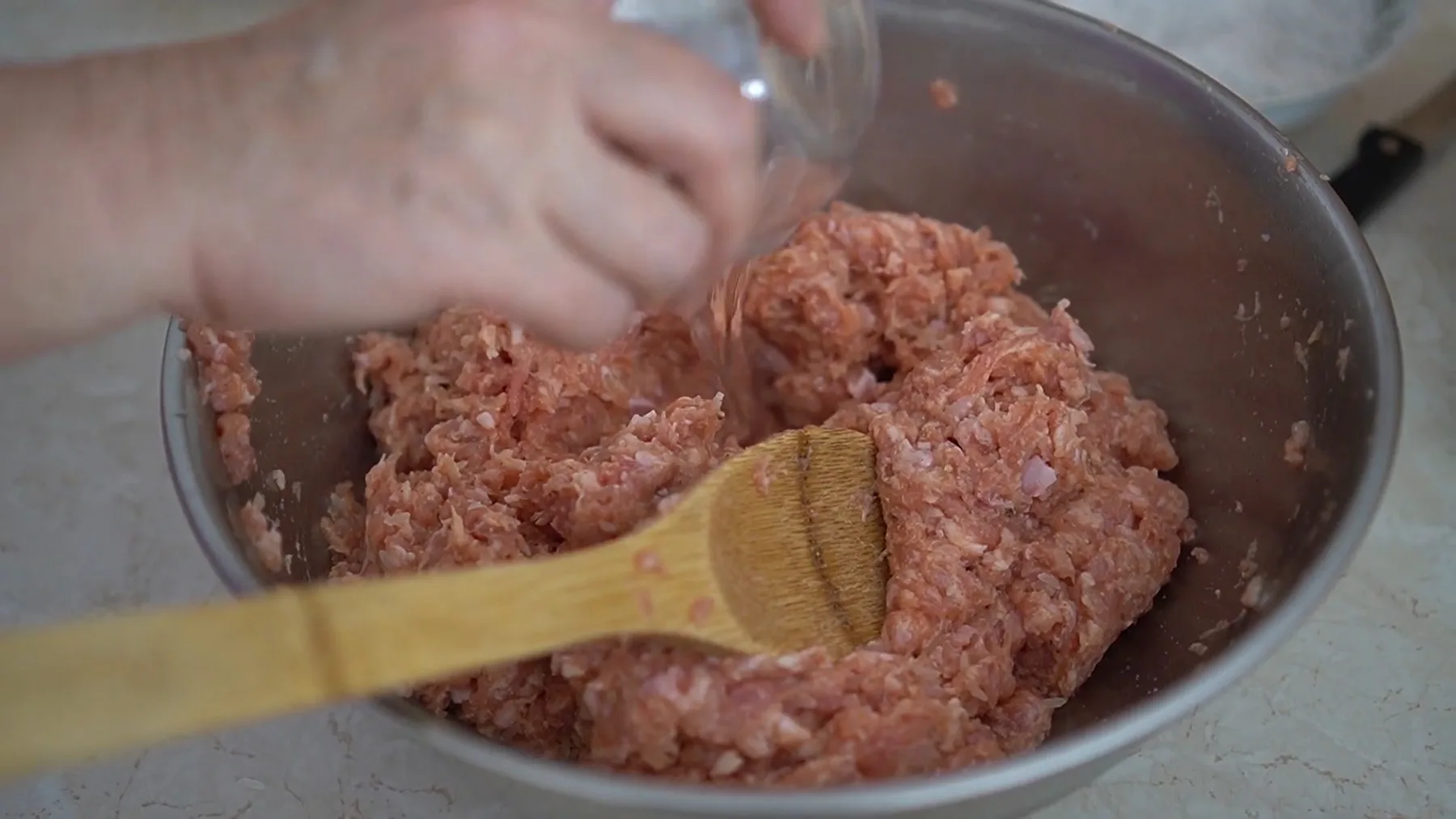 Carne tocată amestecată în bol metalic, cu lingură de lemn