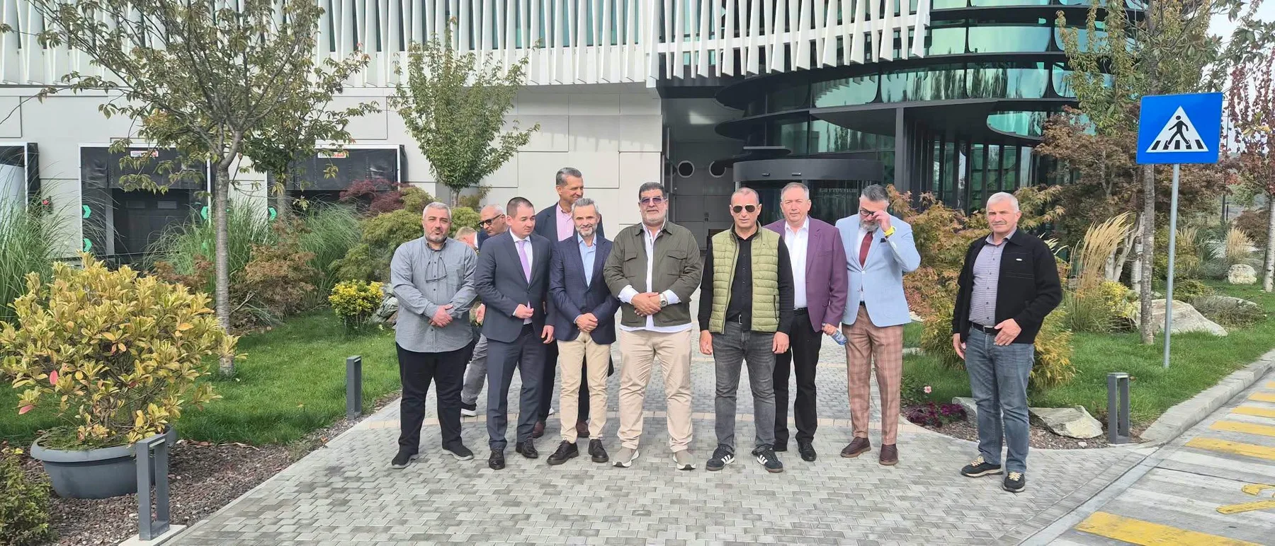 Grup de bărbați în fața unei clădiri, lângă trecere pietonală