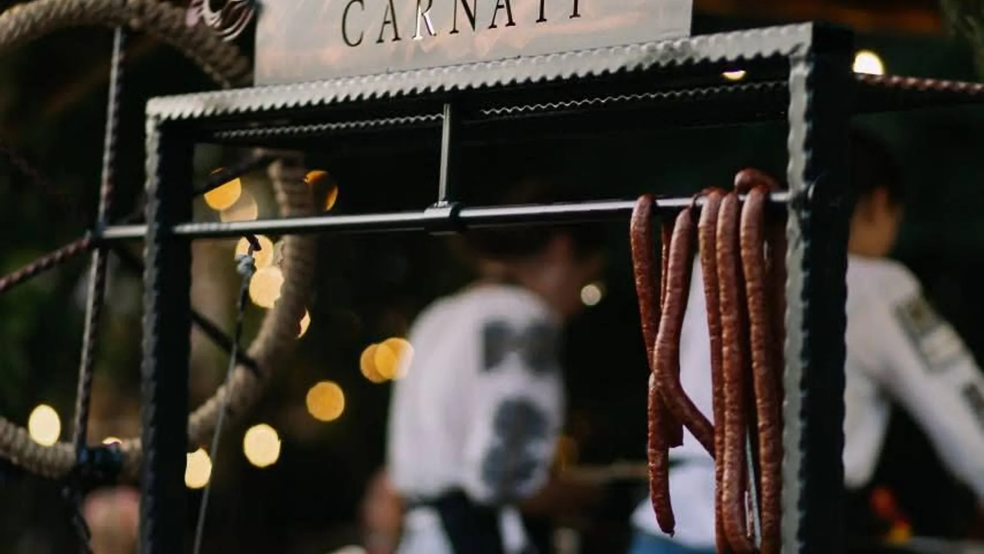 Cârnați afumați atârnați la un stand gastronomic iluminat