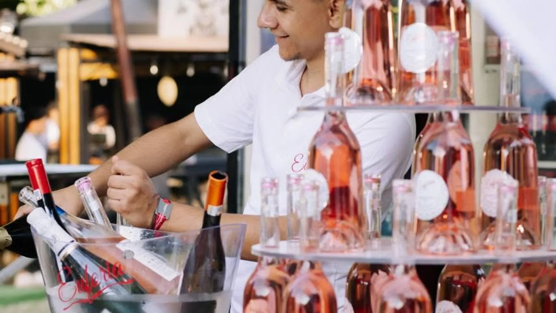 Bărbat la stand cu sticle de vin rosé și frapiere