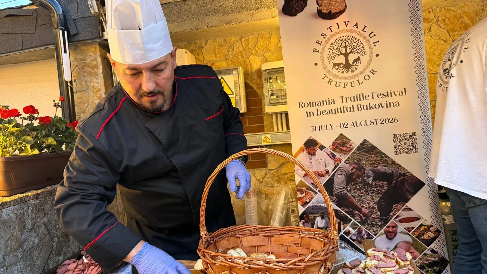 Bucătar cu mănuși lângă coș și afișul Festivalului Trufelor