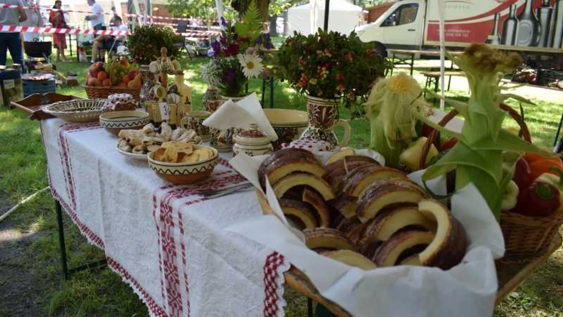 Masă cu produse de patiserie, aranjamente florale și decoruri populare