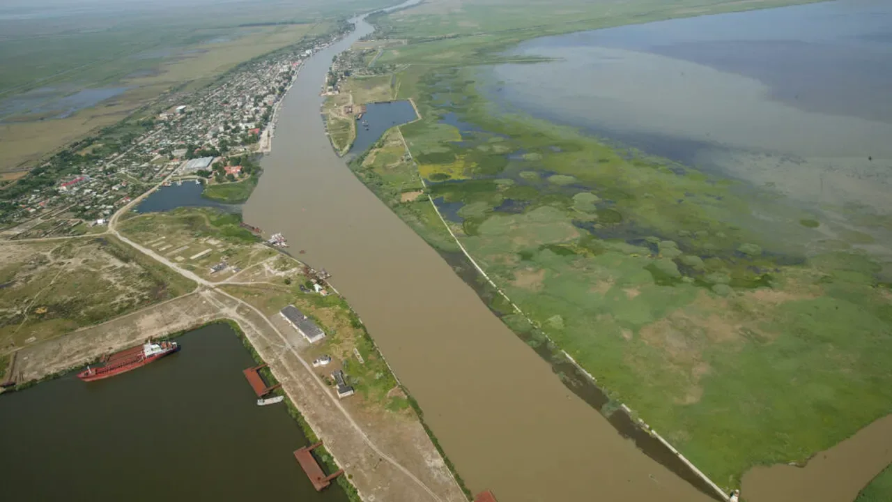 Braț al Dunării traversând Delta, cu localitate, zone umede și lacuri