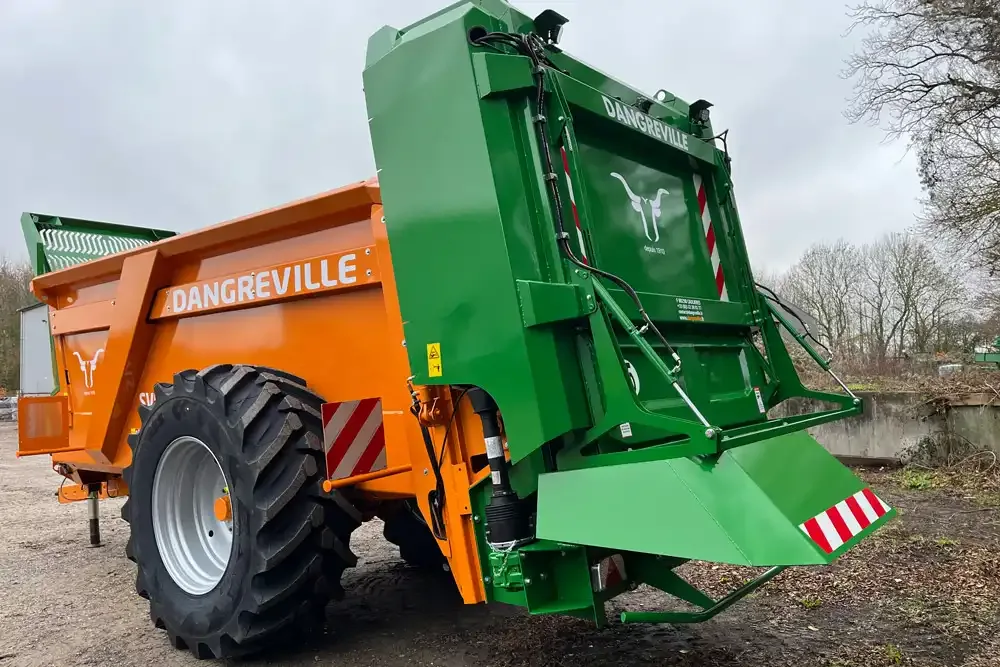 Distribuitor Dangreville verde și portocaliu, văzut din spate, pe teren pietruit